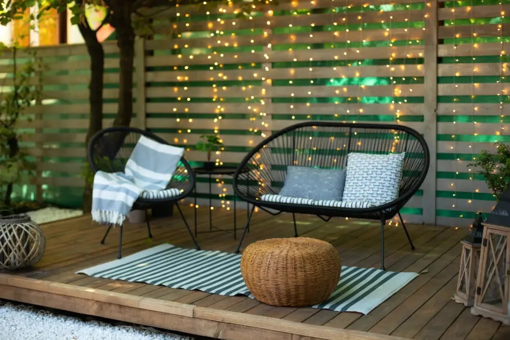 salon-moderno-al-aire-libre-patio-trasero-sofa-negro-sillon-pared-madera-mesa